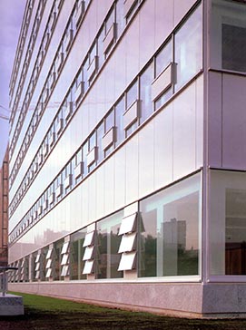 El edificio se asienta sobre un zócalo de granito gris abujardado. La planta baja se configura como basamento en el que la superposición vertical alterna de elementos opacos refuerza la imagen clásica de edificio asentado sobre sólidos pilares.
