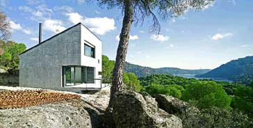 La casa se asienta en lo alto de la parcela, sobre un pequeño barranco granítico desde el que disfrutar del panorama del pantano y el bosque